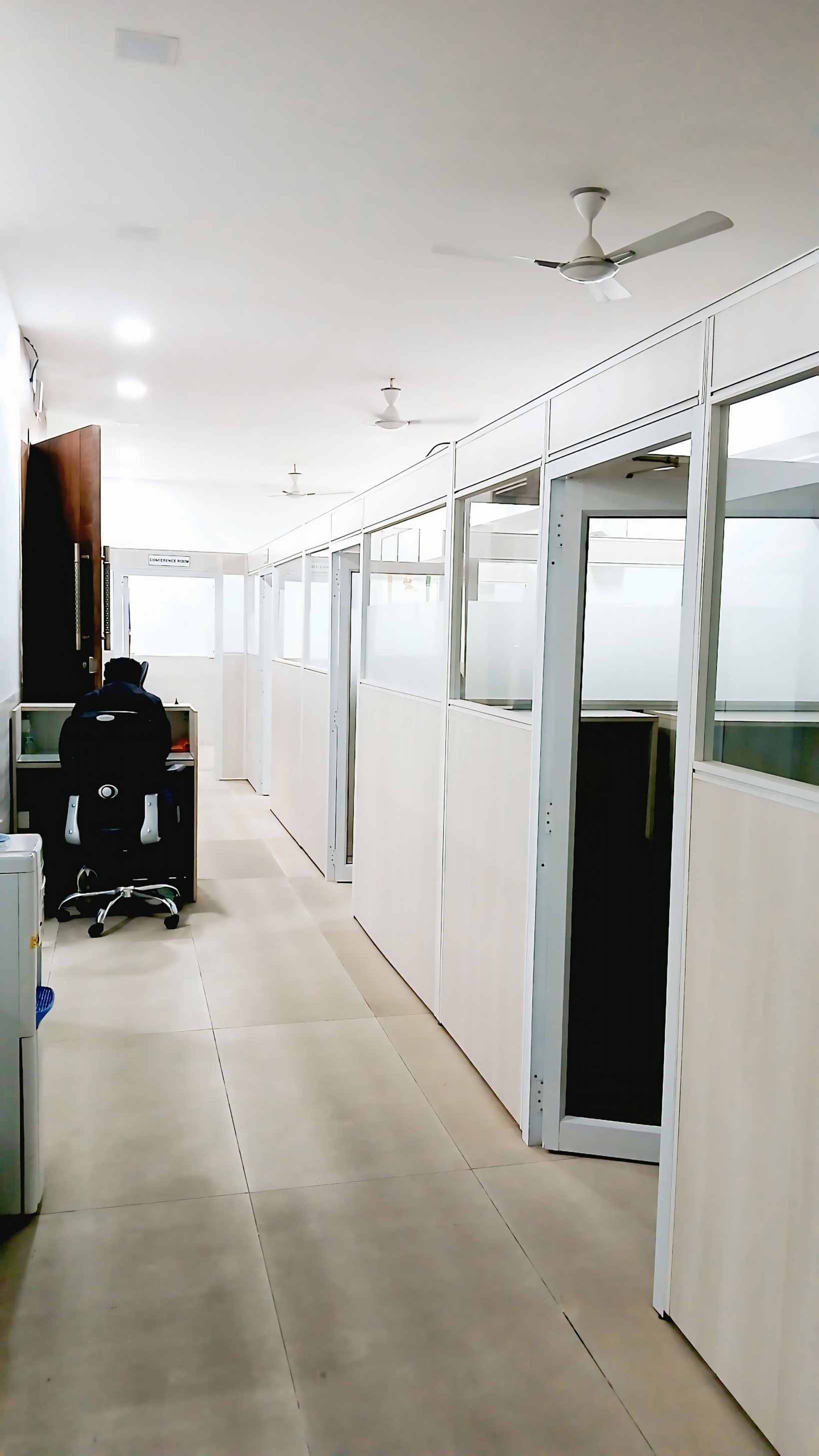 Office corridor lined with glass-partitioned cabins and a conference room