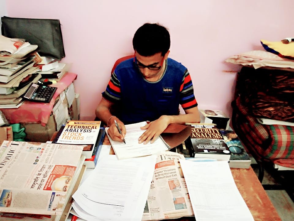 Founder studying at a desk surrounded by books and newspapers in 2019
