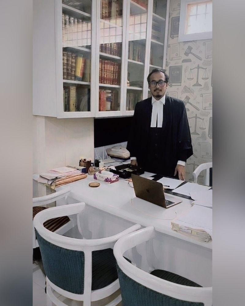 Founder in robes behind a desk at the new office with law-themed décor