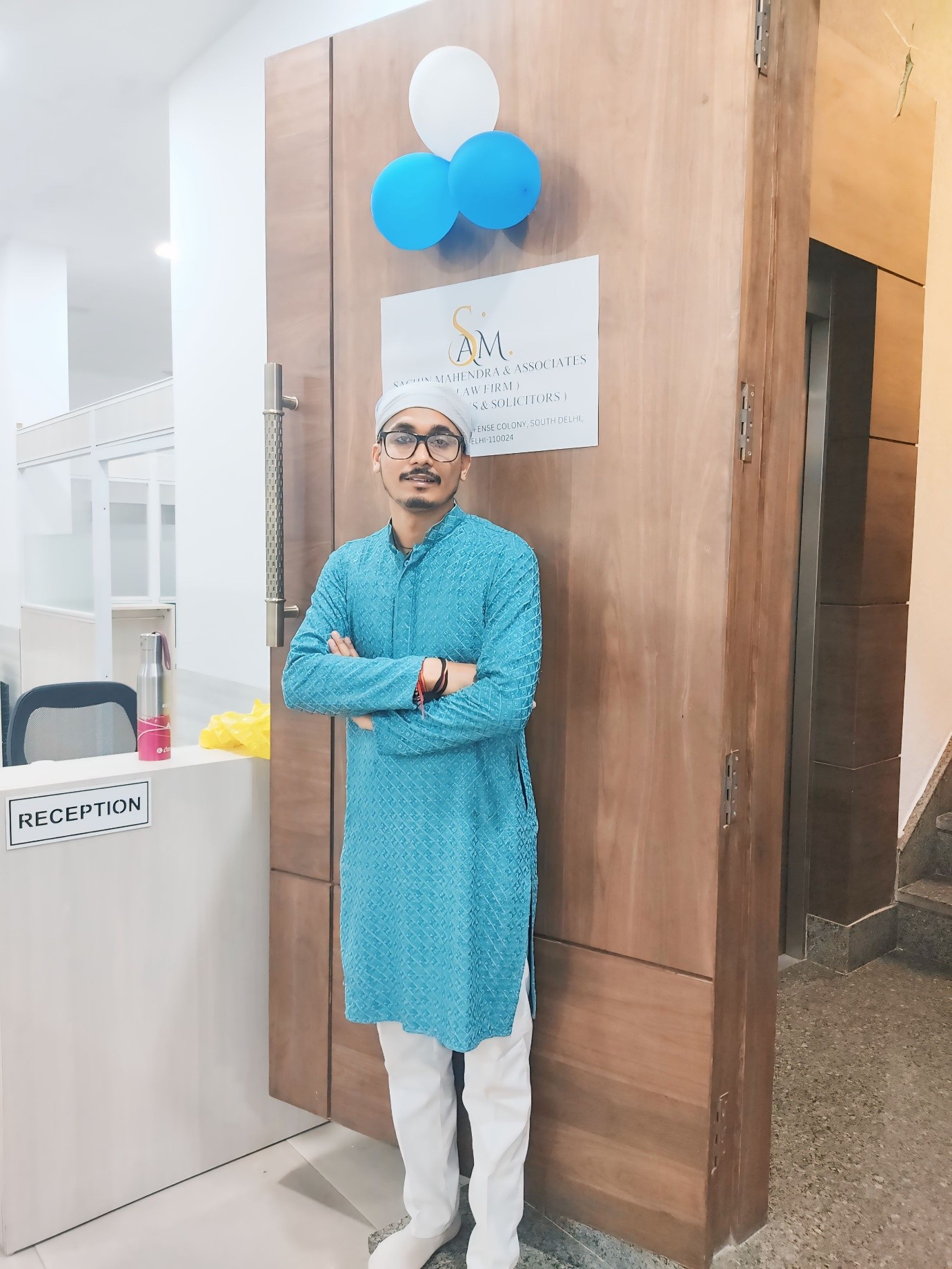 Founder beside the Sachin Mahendra & Associates reception signage at the Defence Colony office