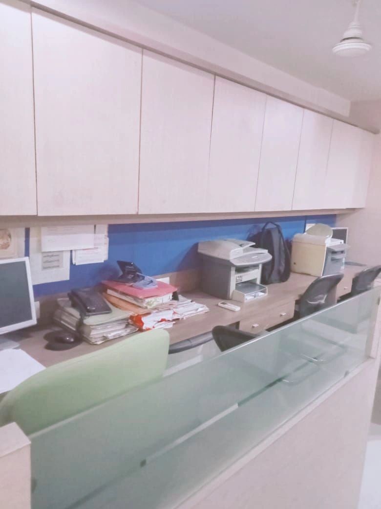 Office workstations with files, monitors and printers along a desk